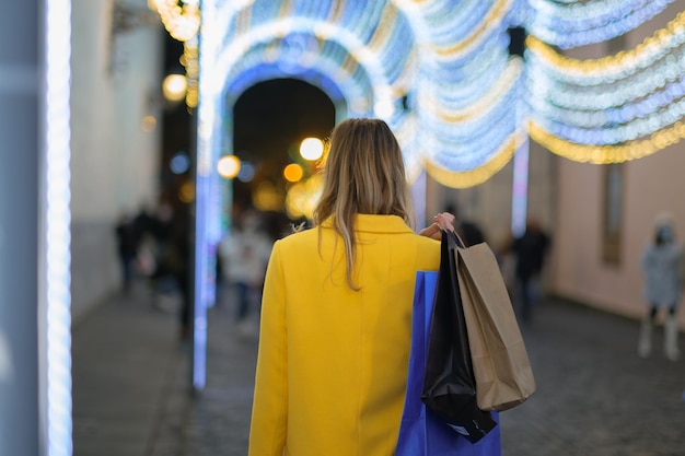 Giovane donna sulla schiena che trasporta borse della spesa durante il Natale