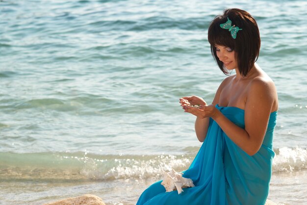 Giovane donna sulla spiaggia con pietre in mano