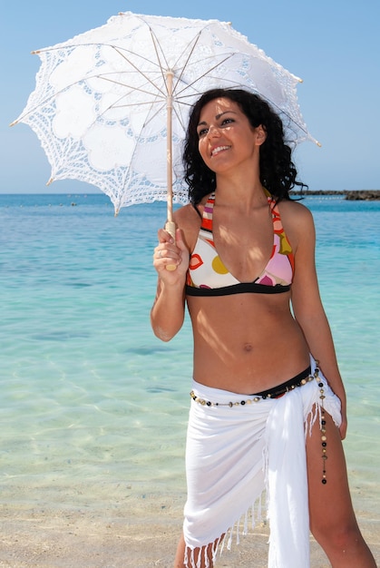 giovane donna sulla spiaggia godendo il bel tempo vicino al mare con il suo ombrellone.