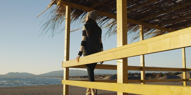 Giovane donna sulla spiaggia. La ragazza che si gode la calda giornata autunnale. Ritratto di bella ragazza vicino all'acqua