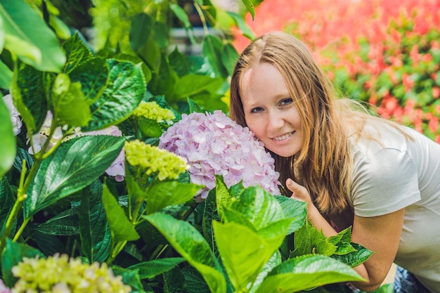 Giovane donna sullo sfondo di fiori di ortensia rosa chiaro che sbocciano nel giardino