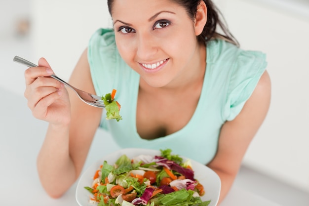 Giovane donna sveglia che mangia insalata