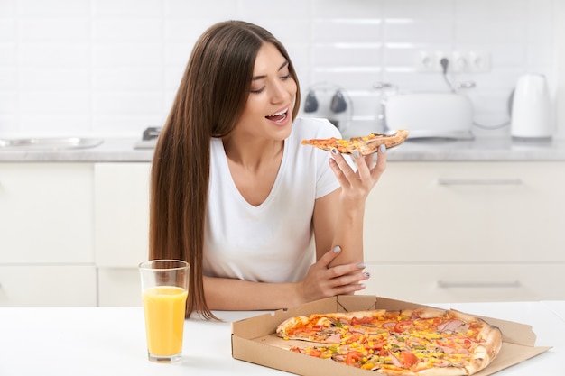 Giovane donna sveglia che mangia pizza saporita