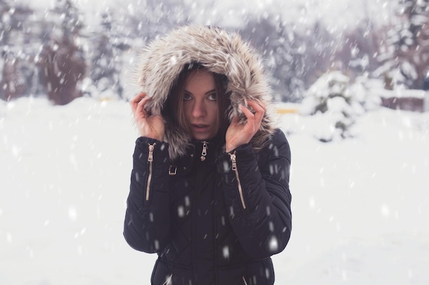 Giovane donna sveglia sotto i fiocchi di neve in inverno