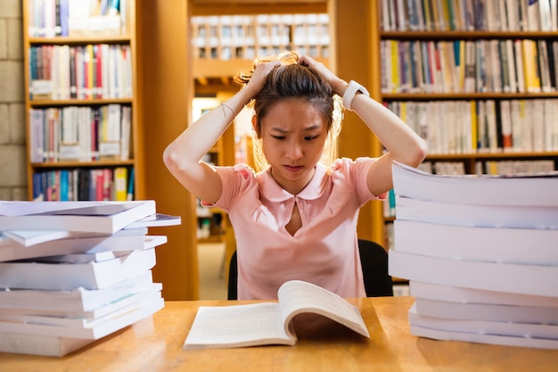 Giovane donna tesa che studia nella biblioteca