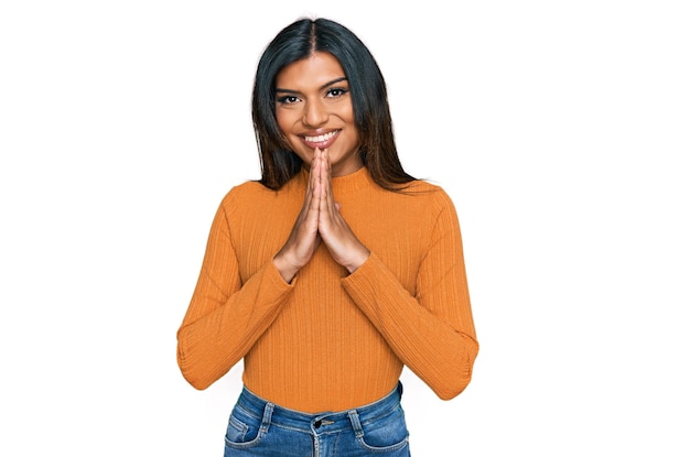 Giovane donna transgender transessuale latina che indossa abiti casual pregando con le mani insieme chiedendo perdono sorridendo fiducioso.