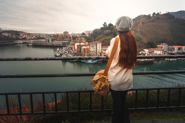 Giovane donna turistica caucasica che esamina la baia da un punto di vista elevato a Pasaia; Paesi Baschi.