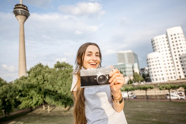 Giovane donna turistica in piedi con la macchina fotografica con la famosa torre della televisione e gli edifici moderni nella città di Dusseldorf, Germany