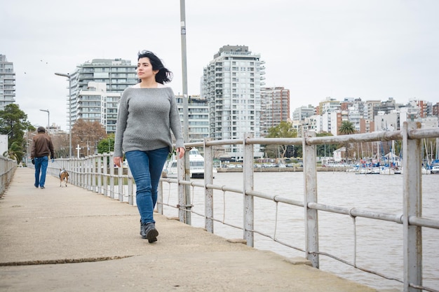 Giovane donna turistica latina che cammina sul molo sopra il fiume a Buenos Aires