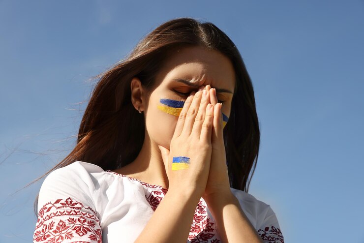 Foto giovane donna ucraina con le mani giunte contro il cielo blu