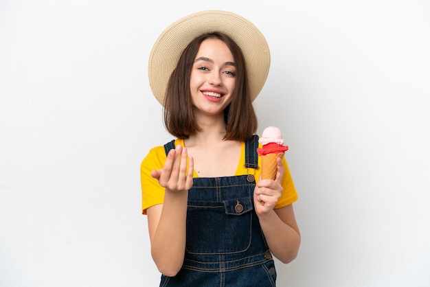 Giovane donna ucraina con un gelato alla cornetta isolato su sfondo bianco che invita a venire con la mano Felice che tu sia venuto