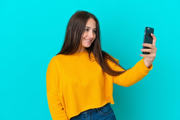 Giovane donna ucraina isolata su sfondo blu che fa un selfie