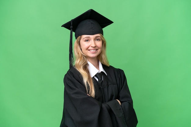 Giovane donna universitaria inglese laureata su sfondo isolato con le braccia incrociate e guardando avanti