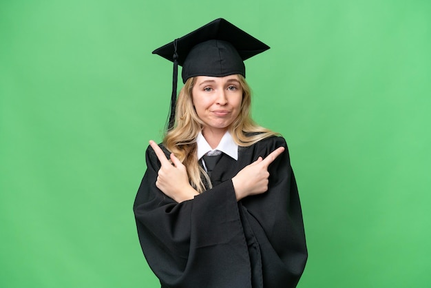 Giovane donna universitaria laureata in inglese su sfondo isolato che punta ai laterali che hanno dubbi