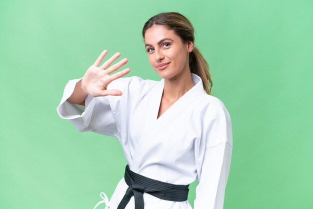 Giovane donna uruguaiana che fa karate su sfondo isolato contando cinque con le dita