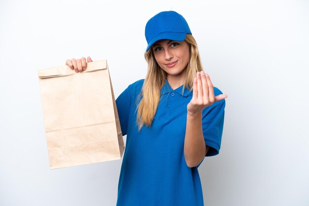 Giovane donna uruguaiana che prende un sacchetto di cibo da asporto isolato su sfondo bianco che invita a venire con la mano Felice che tu sia venuto