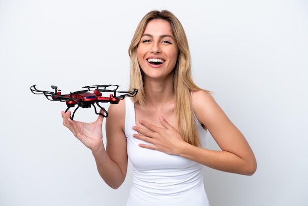 Giovane donna uruguaiana che tiene un drone isolato su sfondo bianco che sorride molto