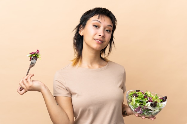 Giovane donna uruguaiana con insalata sopra la parete isolata