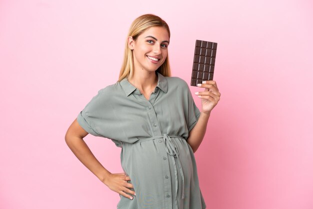 Giovane donna uruguaiana isolata su sfondo blu incinta e in possesso di cioccolato
