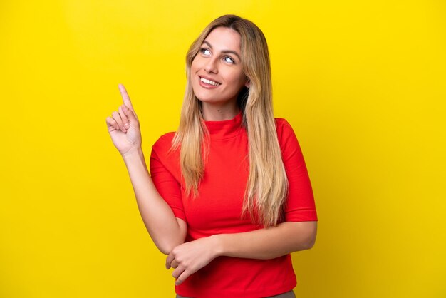 Giovane donna uruguaiana isolata su sfondo giallo che punta su una grande idea