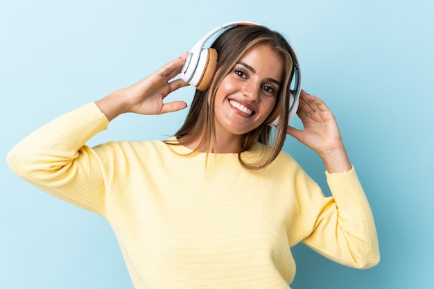 Giovane donna uruguaiana isolata sulla musica d'ascolto della parete blu