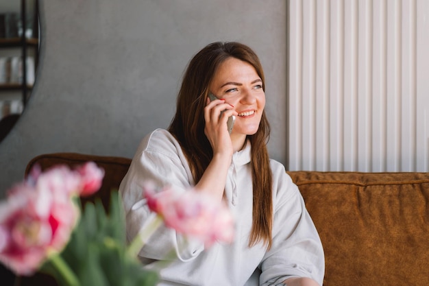 Giovane donna usa il telefono cellulare Bevi caffè e siediti da solo al tavolo nella caffetteria