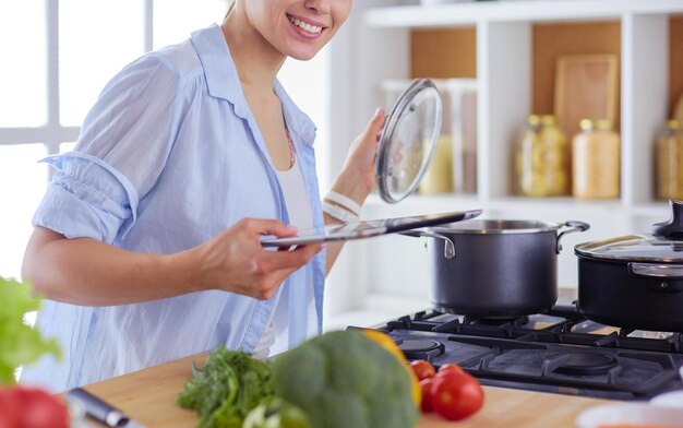 Giovane donna utilizzando un tablet PC per cucinare nella sua cucina