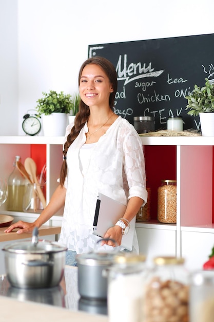 Giovane donna utilizzando un tablet PC per cucinare nella sua cucina