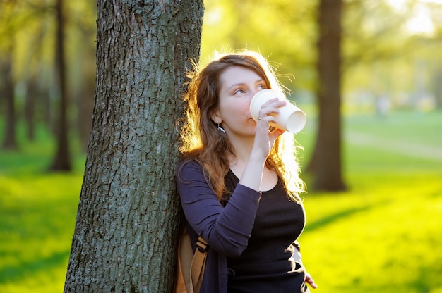 Giovane donna vaga che beve caffè o tè all&#39;aperto