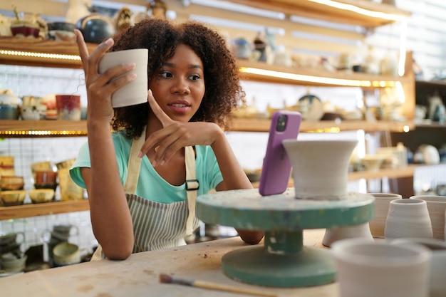Giovane donna vasaio a mano che fa vaso di argilla nel laboratorio di ceramica Imprenditore