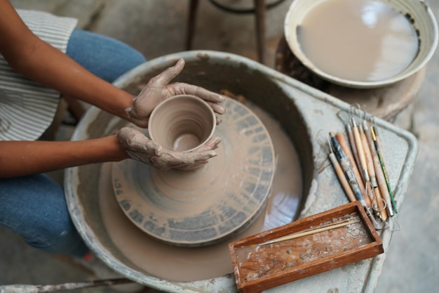 Giovane donna vasaio a mano che fa vaso di argilla nel laboratorio di ceramica Imprenditore