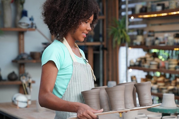 Giovane donna vasaio a mano che fa vaso di argilla nel laboratorio di ceramica Imprenditore