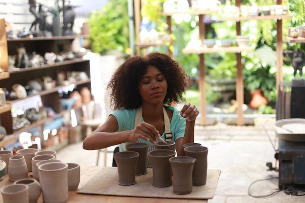 Giovane donna vasaio a mano che fa vaso di argilla nel laboratorio di ceramica Imprenditore