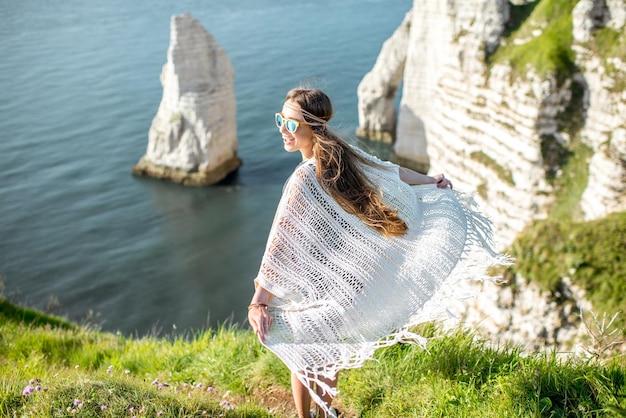 Giovane donna vestita in stile hippie che si gode la natura sulla costa rocciosa con una splendida vista sull'oceano in Francia