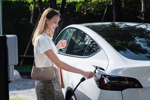 Giovane donna viaggia con un'auto elettrica EV nelle interiorità di una città sostenibile e verde