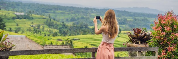 Giovane donna viaggiatore sulle bellissime terrazze di riso Jatiluwih sullo sfondo dei famosi vulcani di Bali, Indonesia BANNER, formato lungo