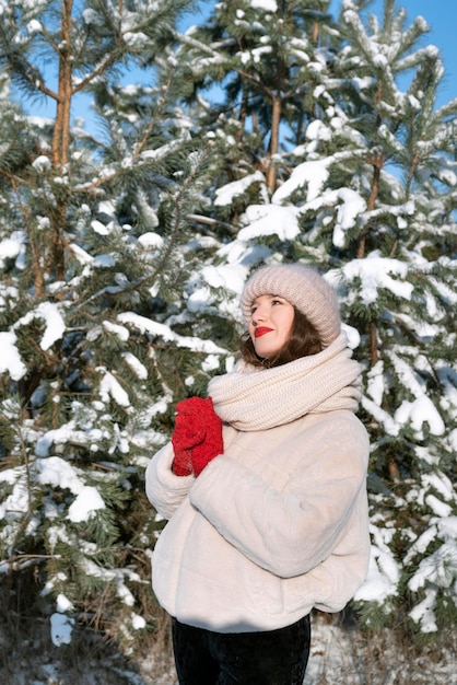 Giovane donna vicino ad alberi innevati. Cornice verticale.