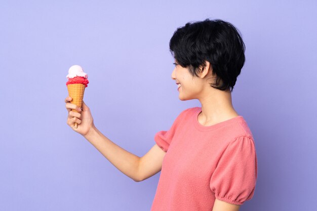 Giovane donna vietnamita con i capelli corti che tiene un grande dolce sulla porpora isolata