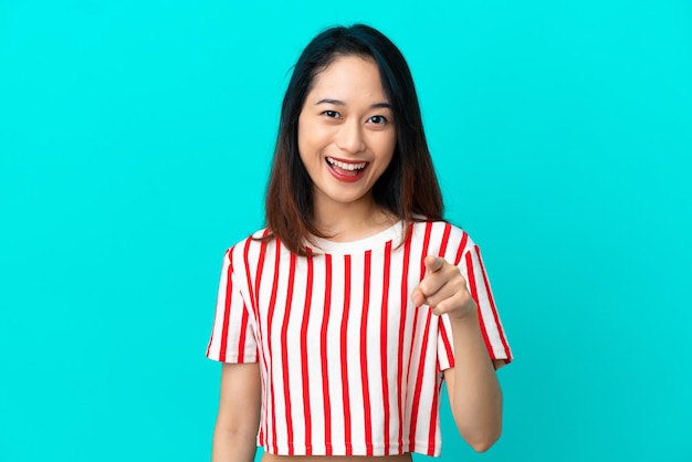 Giovane donna vietnamita isolata su sfondo blu sorpreso e puntato davanti