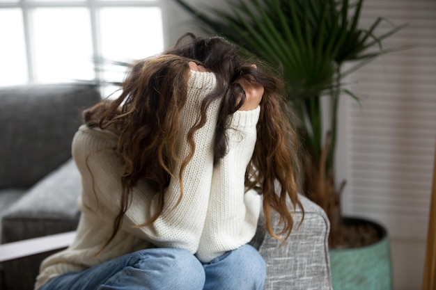 Giovane donna vittima di abusi, molestie, depressione o dolore, adolescente triste e disperata, che ha problemi a tenere la testa tra le mani, ragazza sconvolta e con il cuore spezzato, che piange, che ha una pericolosa dipendenza.