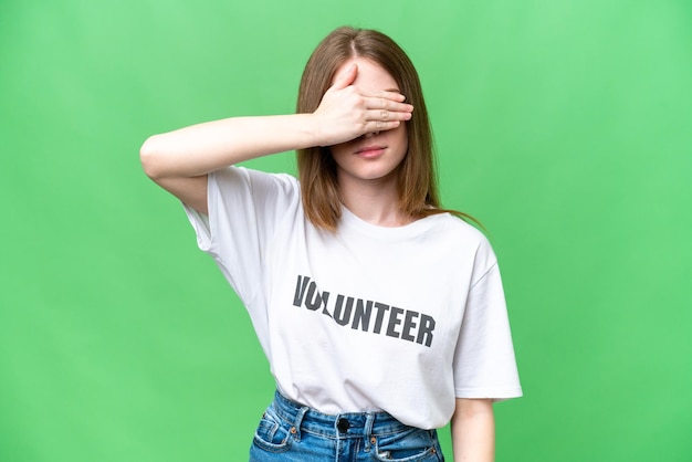 Giovane donna volontaria su sfondo chroma key isolato che copre gli occhi con le mani Non voglio vedere qualcosa