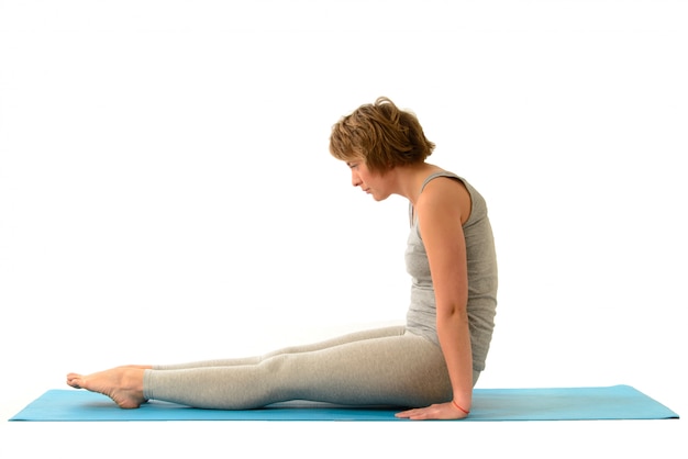 Giovane donna yoga impegnata nello yoga. Isolato sul muro bianco