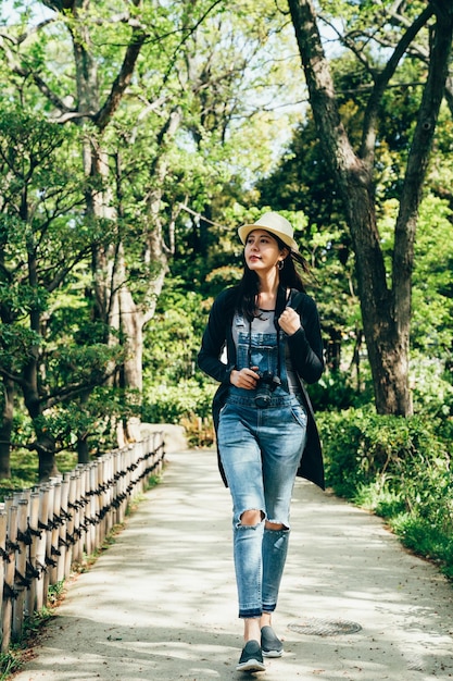 giovane donna zaino in spalla che cammina nel giardino giapponese. per tutta la lunghezza del fotografo della ragazza che respira aria fresca nella foresta verde di nihon teien. percorso con splendidi alberi della natura intorno.