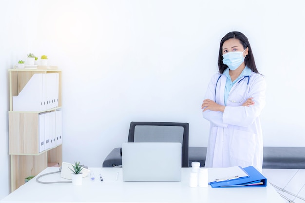 Giovane dottoressa che indossa una maschera facciale mentre lavora nel suo ufficio. Sanità e concetto medico.