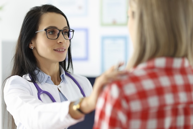 Giovane dottoressa che tiene il paziente per la spalla in clinica assistenza medica psicologica