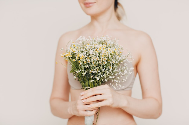 Giovane e bella donna bionda con bouquet di camomilla. Concetto di eco-cosmesi naturale