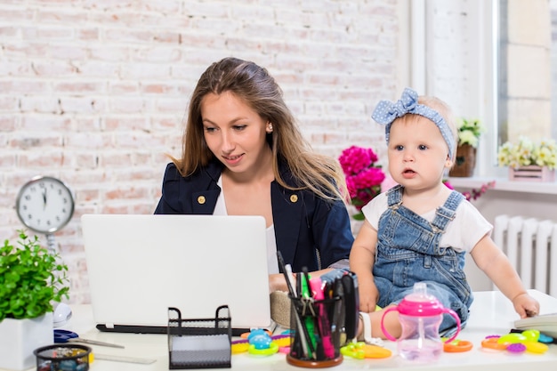 Giovane e bella donna d'affari allegra che guarda il laptop mentre è seduta al suo posto di lavoro con lei