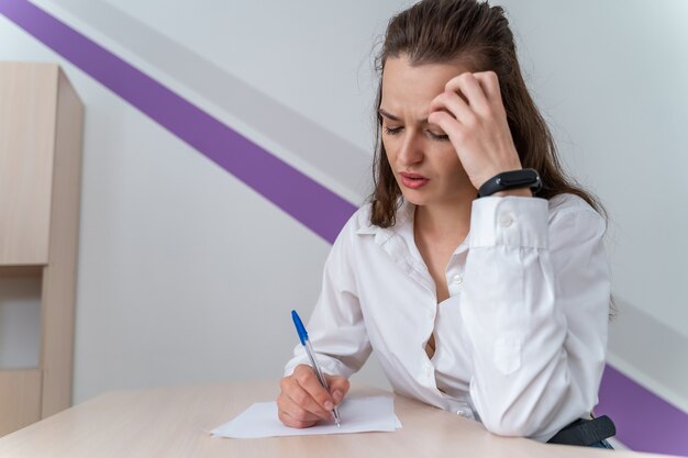 Giovane e bella donna d'affari stanca dal lavoro in ufficio