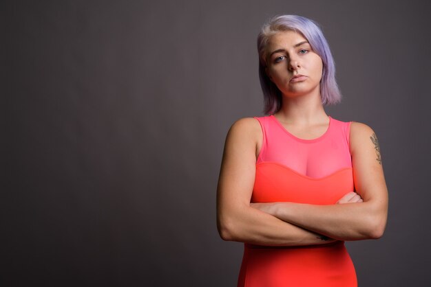 giovane e bella donna ribelle con i capelli colorati che indossa un abito rosso neon