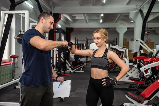 Giovane e bella istruttore di fitness sexy organizza lezioni di fitness per ragazze che vogliono perdere peso Il concetto di allenamento in palestra